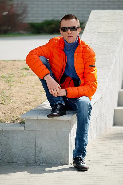 一男子在橙色的夹克衫和蓝色牛仔裤的肖像 — 图库照片