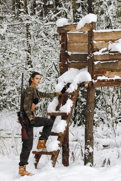 Menina caçador atraente com rifle na torre de caça no inverno para — Fotografia de Stock