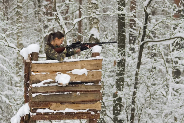 Atractiva chica cazador con rifle en la torre de caza en invierno para — Foto de Stock