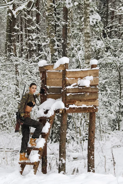 Menina caçador atraente com rifle na torre de caça no inverno para — Fotografia de Stock