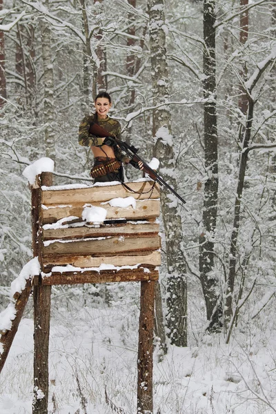 Atractiva chica cazador con rifle en la torre de caza en invierno para — Foto de Stock