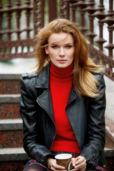 Retrato de señora de pelo rojo en chaqueta de cuero con taza de cartón — Foto de Stock