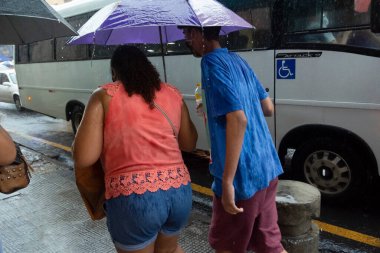 Salvador, Bahia, Brezilya - 09 Nisan 2021: Şiddetli yağmurda şemsiyelerle yürüyen iki kişi.