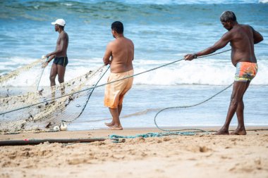 Salvador, Bahia, Brezilya - 23 Mayıs 2021: Balıkçılar denizden balık ağlarını çekiyorlar. Salvador 'daki Boca do Rio plajı.