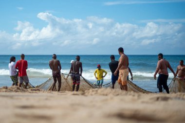 Salvador, Bahia, Brezilya - 23 Mayıs 2021: Balıkçılar denizden balık ağlarını çekiyorlar. Salvador 'daki Boca do Rio plajı.