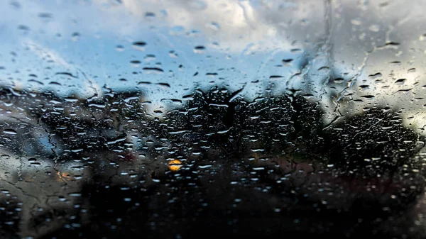 Bokeh, rain, drops of water through the car window. Rainy day. Defocused car flashlights. Colorful.