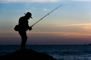 Salvador, Bahia, Brezilya - 25 Nisan 2021: Balıkçıların balık avlamak için kayalıklarda oltaları olan silueti.