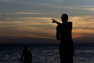 Salvador, Bahia, Brezilya - 25 Nisan 2021: Salvador, Bahia 'daki Rio Vermelho plajındaki kayalıklarda yaşayan balıkçıların silueti yiyecek ve ailelerine destek arıyorlar.