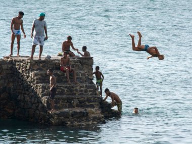 Salvador, Bahia, Brezilya - 08 Ocak 2019: Porto da Barra 'daki Forte de Santa Maria iskelesinden denize atlayan gençler.