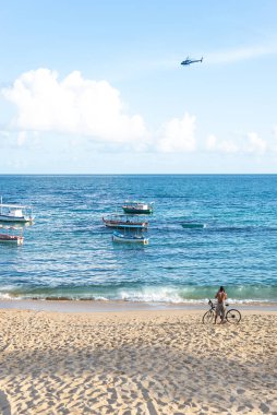 Salvador, Bahia, Brezilya - 30 Mayıs 2021: Güneşli bir günde Rio Vermelho sahilinde bisikletli bir adam.