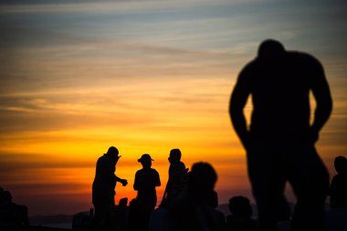 Salvador, Bahia, Brezilya - 12 Haziran 2021: Salvador, Bahia 'da Farol da Barra' nın muhteşem renkli günbatımının tadını çıkaran insanların silueti.