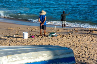 Salvador, Bahia, Brezilya - 25 Nisan 2021: Gün batımında sırıkları ile balıkçıların silueti.