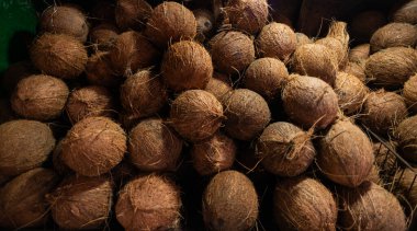 İnce lifli kabuklu kahverengi hindistan cevizlerine yakın çekim. Kaba dokuları ve toprak rengini gösteriyor. Tropikal üretime odaklanan resim bankaları için ideal