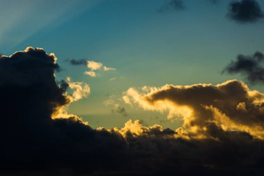 A dramatic sunset over a calm sea, with heavy clouds parting to reveal brilliant sunbeams. A warm, golden light.
