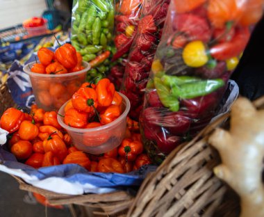Canlı yeşil ve kırmızı biberler kalabalık bir pazarda kırsal bir hasır sepetten dökülüyor. Sağlıklı beslenme.