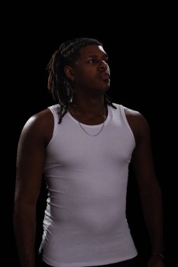 Rasta bukleli ve beyaz gömlekli yakışıklı bir genç fotoğraf çekimi sırasında yan tarafa bakıyor. Dumanlı bir arka planda izole edilmiş. Fotoğraf modeli