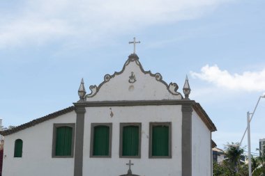 Salvador, Bahia, Brezilya - 2 Kasım 2025: Salvador, Bahia 'da Rio Vermelho mahallesinde yeşil pencereli ve haçlı beyaz bir koloni kilisesi cephesi.