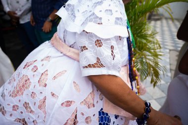 Salvador, Bahia, Brezilya - 25 Kasım 2025: Baiana de Acaraj 'ın elleri ve gövdesine yakın çekim Pelourinho, Salvador, Bahia' da düzenlenen Baiana Günü kutlamalarına katılıyor..