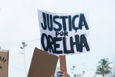 Salvador, Bahia, Brezilya - 1 Şubat 2026: Bir grup genç aktivist, Barra plajı boyunca ellerinde Orelha için adalet isteyen el yapımı levhalarla yürüyorlar. Salvador, Bahia.