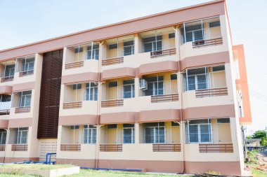 Krem renkli üç katlı binanın arkasında.