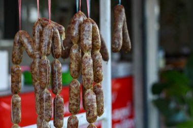 Mayalanmış Tayland domuz sosisi (Sai Krok Isan) pembe iple güneşte sallanıyor..