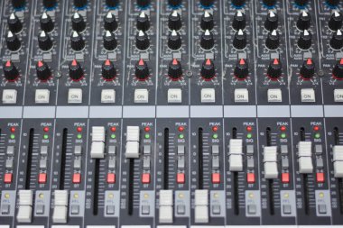 Ses karıştırıcıdaki faders ve düğmelerin yakın görüntüsü.