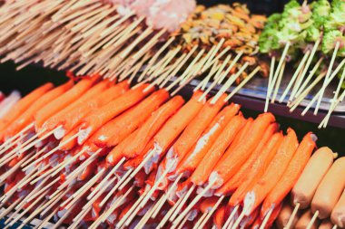 Bir sürü parlak turuncu yengeç bir büfede şişlere yapışıyor..