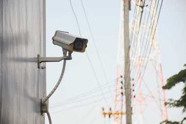 İletişim kulesi arkaplanı olan bir duvardaki CCTV kamerası..