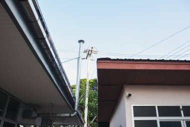 Çatı hatları, bir elektrik direği ve açık bir gökyüzüne karşı kablolar..