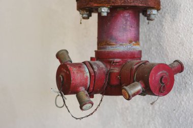 Duvara monte edilmiş paslı kırmızı yangın musluğu..