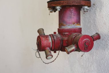 Duvara monte edilmiş paslı kırmızı yangın musluğu..