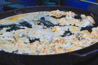 Tayland usulü istiridye omleti büyük bir ızgarada pişiyor..