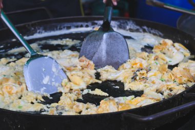 Tayland usulü istiridye omleti büyük bir ızgarada pişiyor..