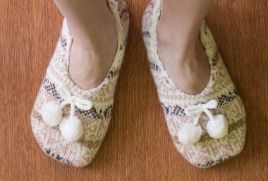 Ahşap zemin üzerinde ponpon ile örgü terlik.