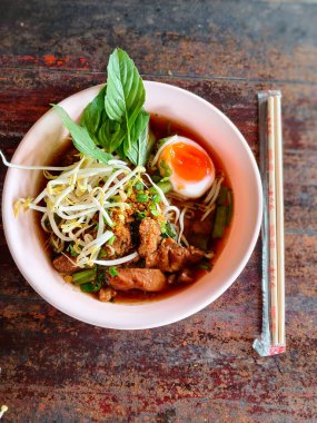 İçinde taze et dilimleri, pirinç eriştesi, fasulye filizi, yeşil soğan, çıtır sarımsak, fesleğen ve yağda kaynamış yağda pişirilmiş yağda yumurta bulunan Tayland usulü şehriye çorbası..