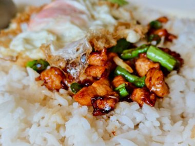 Otantik Tayland gai pad prik 'i tavuk parçaları ve baharatlı soslu fasulye ile sulu sahanda yumurta ve kişniş içerir. Tahta masada kasede servis edilir.