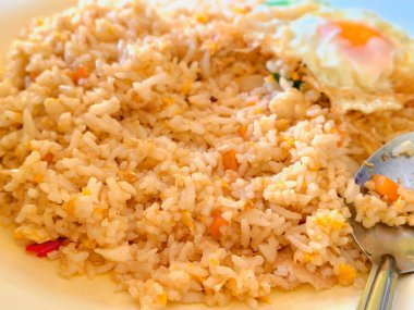 Tayland usulü sade kızarmış pilav çırpılmış yumurta parçaları ve kırmızı biber dilimleriyle karıştırılmış kabarık taneler içerir. Tabakta, sıcak ev tarzında metal kaşıkla servis ediliyor.