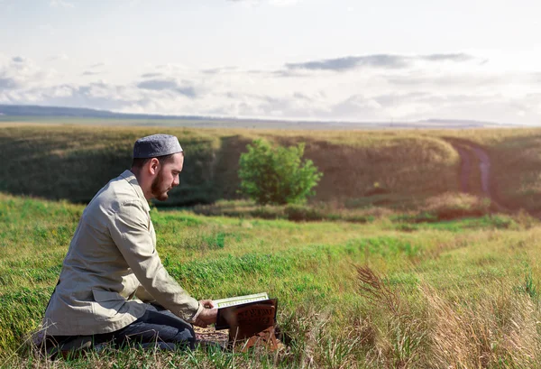 Jovem rezando e lendo o Alcorão Sagrado ao ar livre — Fotografia de Stock