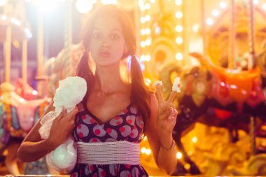 Atlıkarınca 'nın önünde fotoğraf, pamuk şeker, elbiseli kız, sarı ışık, komik yüz, parmaklar, iki numara, barış..