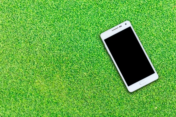 White smart phone with isolated screen on grass background