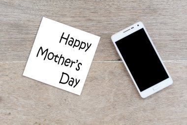 Mutlu anneler günü yazıt ile cep telefonu ahşap arka plan.