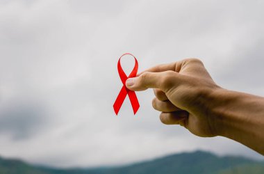 DÜNYA AIDS Günü kavramı. Kırmızı farkındalık kurdeleli genç bir adama yakın çekim..