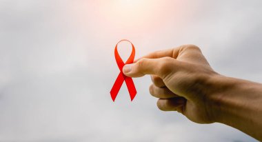 DÜNYA AIDS Günü kavramı. Kırmızı farkındalık kurdeleli genç bir adama yakın çekim..