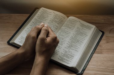 Evdeki İncil için dua eden bir adamın elleri..