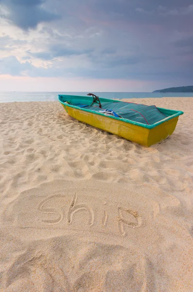 Pequeno barco na praia com placa de areia para escrever — Fotografia de Stock