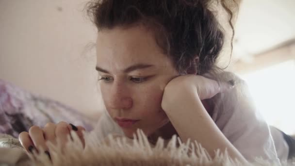 Dziewczyna Domowych Ubraniach Leży Miękkim Łóżku Patrzy Telefon Spoczywa Twarzą — Wideo stockowe