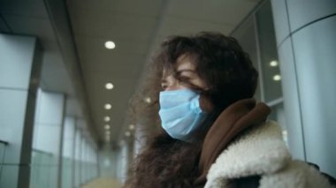 Havaalanında ya da otobüs durağında büyük bir sırt çantasıyla tıbbi maskeli bir kız durup mesafeye bakıyor. İniş için bekler ve çerçeveyi mesafeye bırakır. kamera takip ediyor
