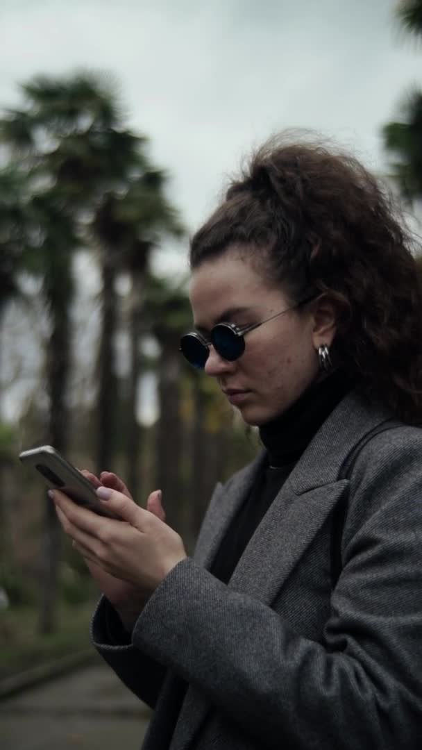 Wanita Berpakaian Muda Berkacamata Biru Melihat Telepon Vertikal Ditembak Seorang — Stok Video