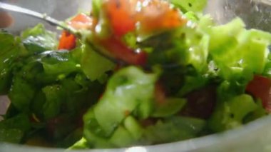 Peynirli domates, yumurta, marul ve zeytinyağlı tohum salatası. Kaşık, vejetaryen yemeğini cam kasede karıştırmak için. Güneşin ışınları ıslak sebzelerin üzerinde parlıyor. Kereviz. Vitaminler ve mineraller