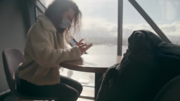 Young Woman White Warm Jacket Medical Mask Sits Table Airport — Stockvideo